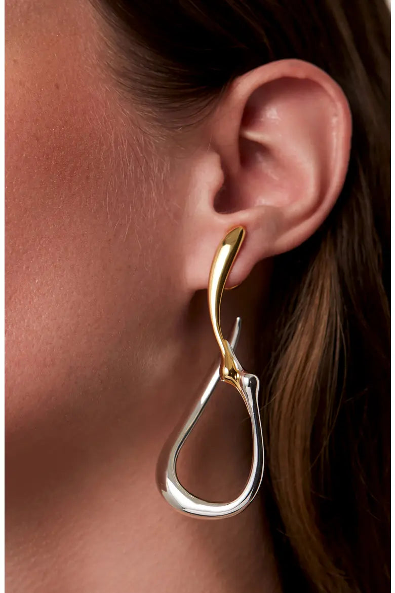 Large two-tone gold and silver sculptural hoop earring worn on ear