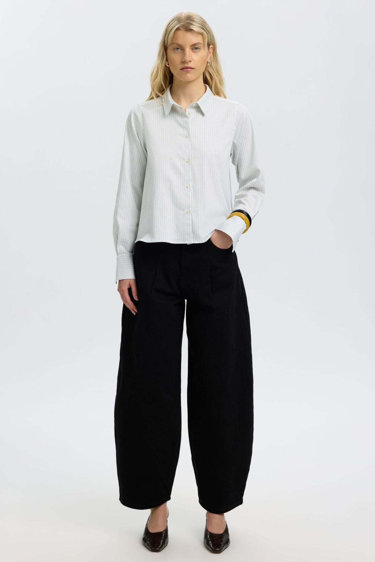 Model wearing Selected SLWROMIE relaxed striped shirt in Avocado Oil Stripes with black wide-leg trousers