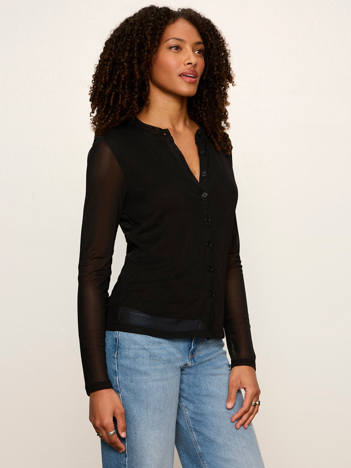 Model wearing Sanctuary black mesh long sleeve cardigan with button front and sheer sleeves