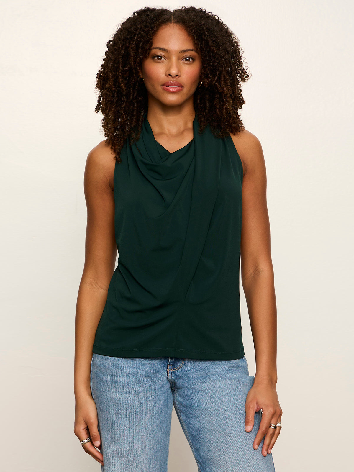 Woman wearing Sanctuary Nora Draped Tank in forest green with cowl neck detail and jeans