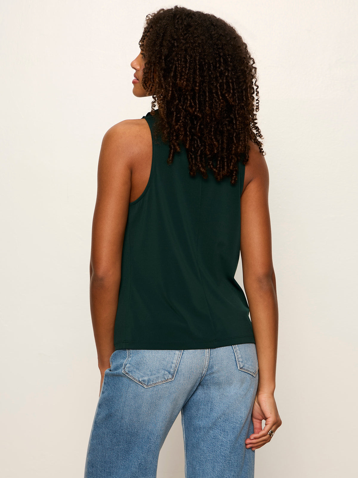 Back view of model wearing Sanctuary Nora Draped Tank in forest green with jeans.