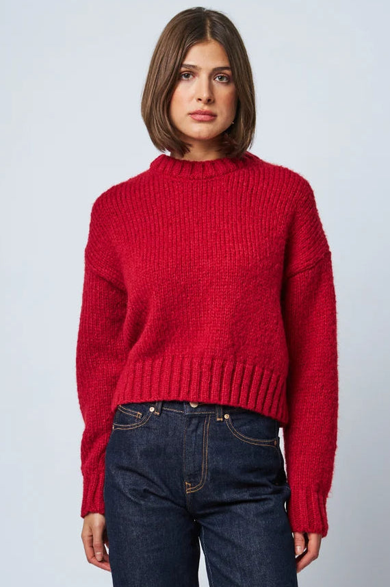 Women's red chunky knit cropped sweater with ribbed hem and cuffs, paired with dark jeans