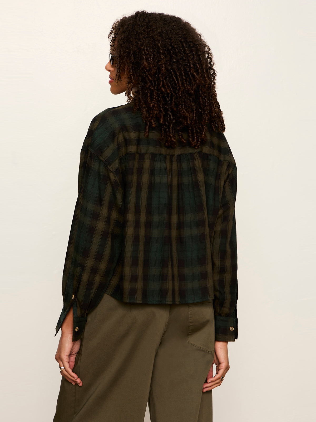 Back view of woman wearing Sanctuary Autumn Edit Flannel shirt in forest plaid with olive trousers