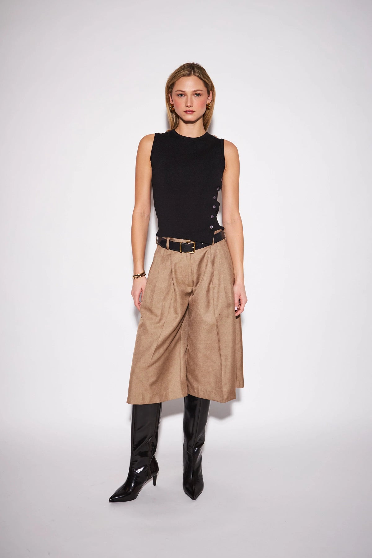 Black sleeveless knit top with side button detail, styled with tan wide-leg culottes and black boots.