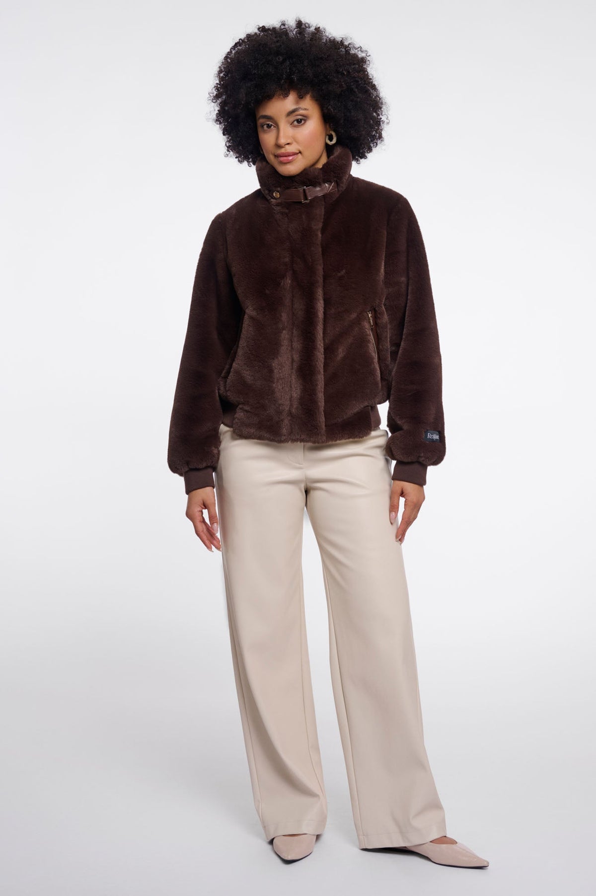 Woman wearing RINO & PELLE Ambra faux fur jacket in Coffee Roast brown with cream trousers