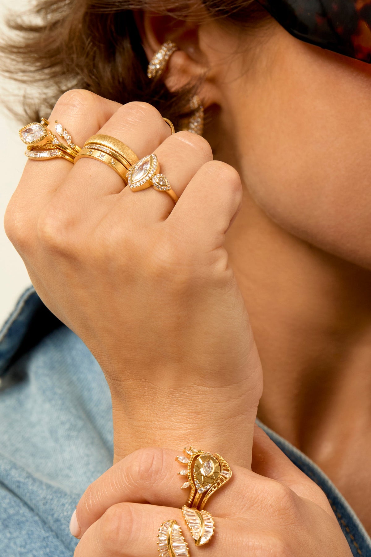 Model wearing multiple gold crystal-embellished rings stacked on fingers, MYA-BAY lifestyle shot