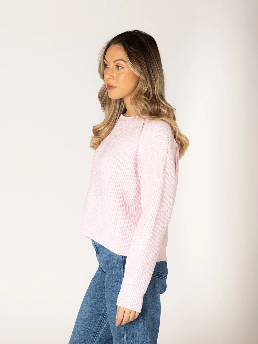 Light pink chenille ribbed crewneck sweater with long sleeves, styled with blue jeans