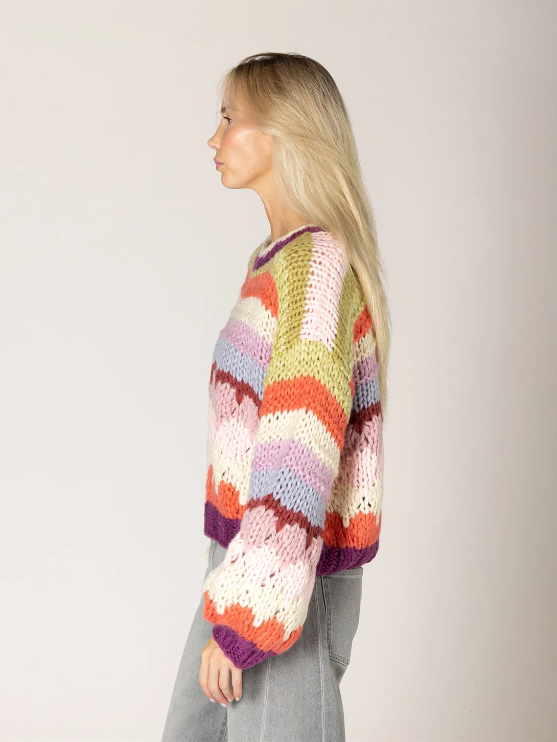 Multicolor chevron stripe chunky knit sweater with purple trim, worn side view