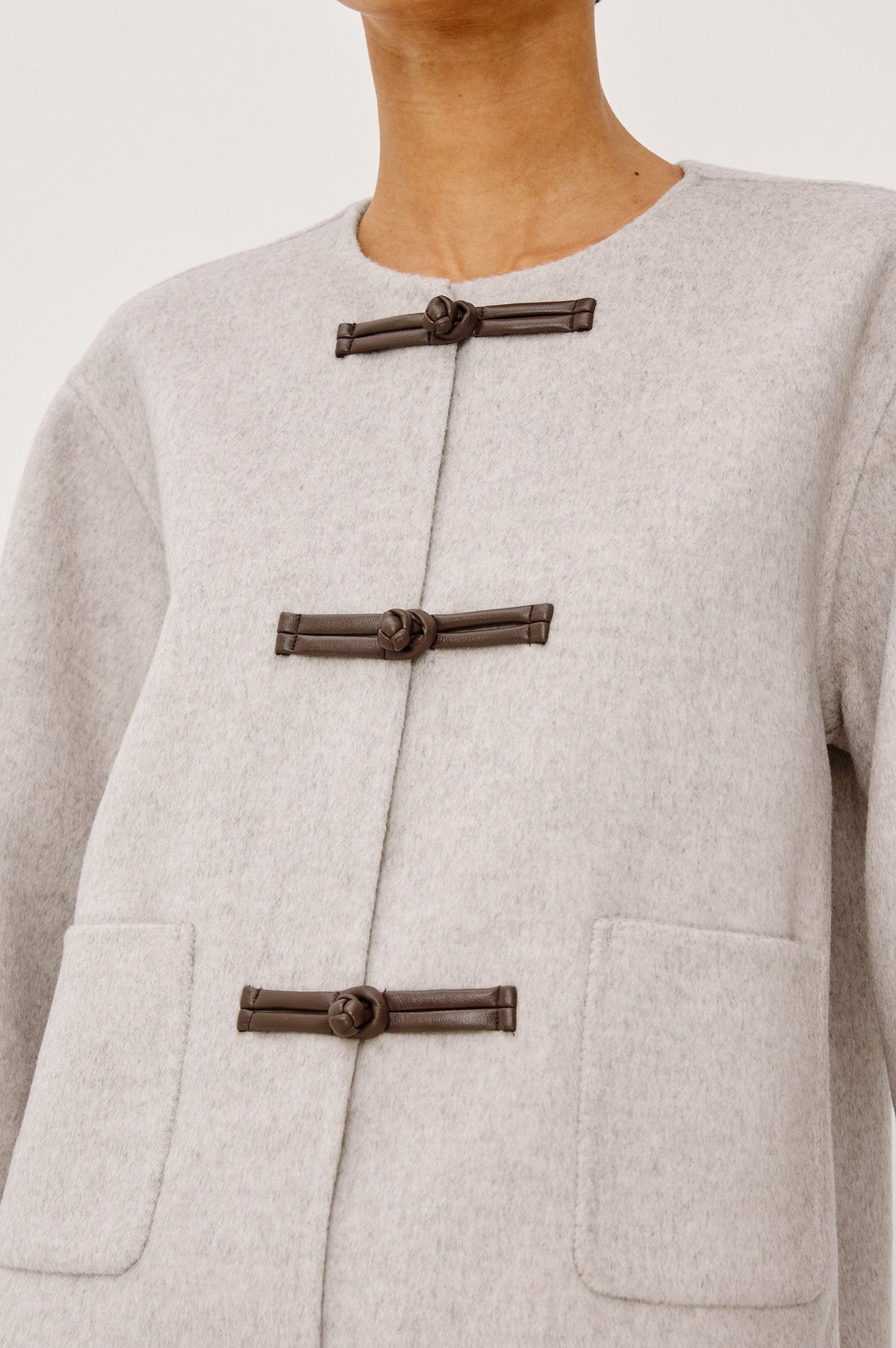 Close-up detail of Rails Deidre coat showing leather toggle closures on heather oat wool fabric
