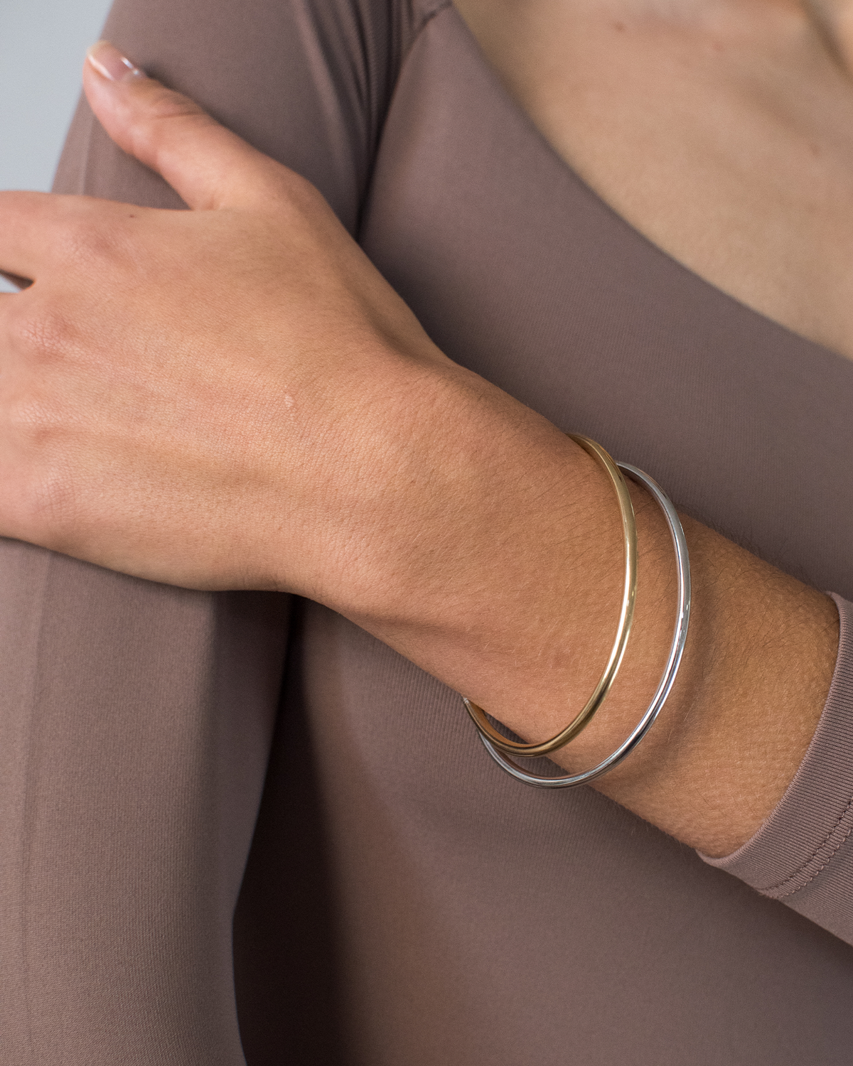 Two-tone gold and silver bangle set worn on wrist, shown in lifestyle close-up shot