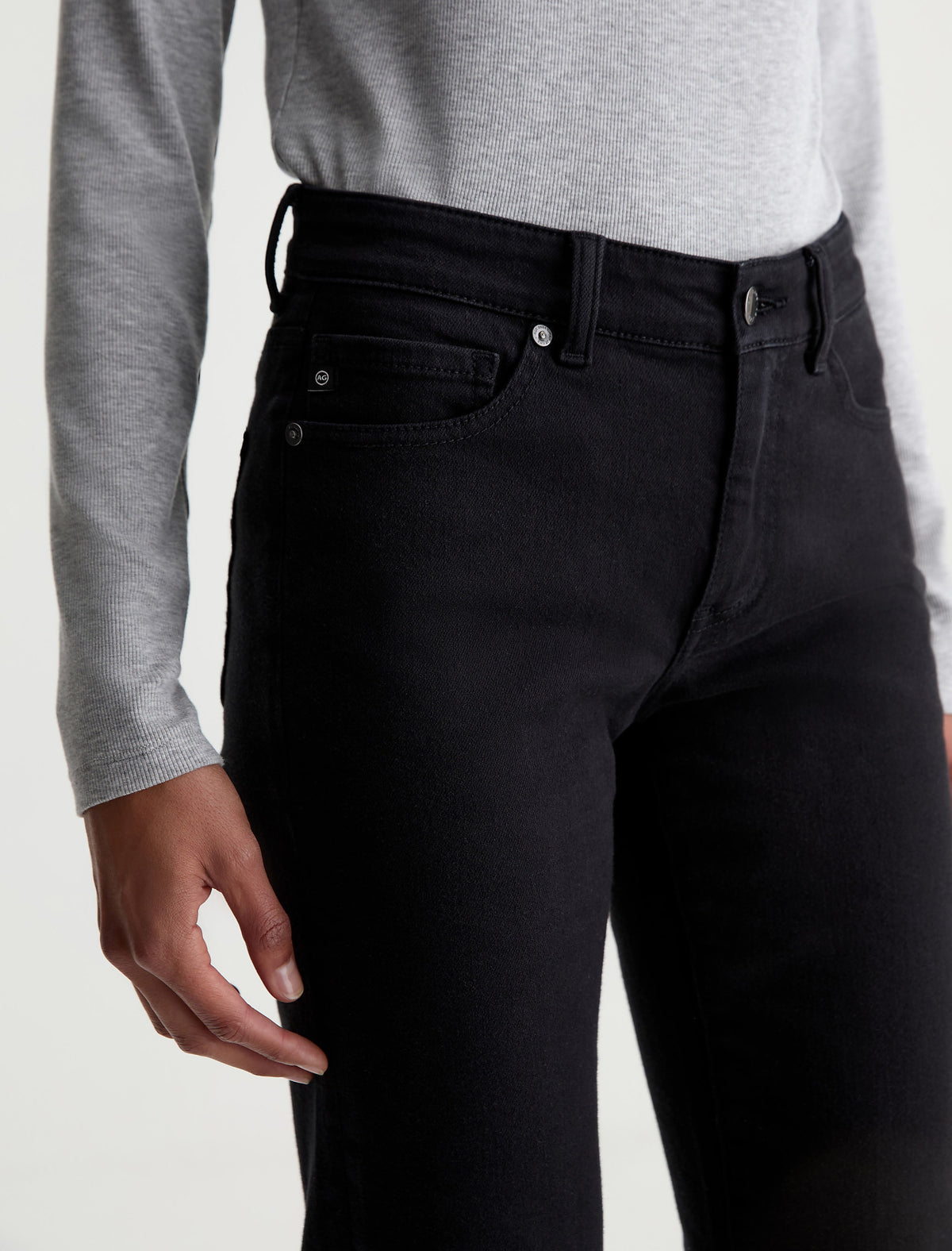Close-up detail of AG Sandra high-rise jeans in super black showing waistband and pocket