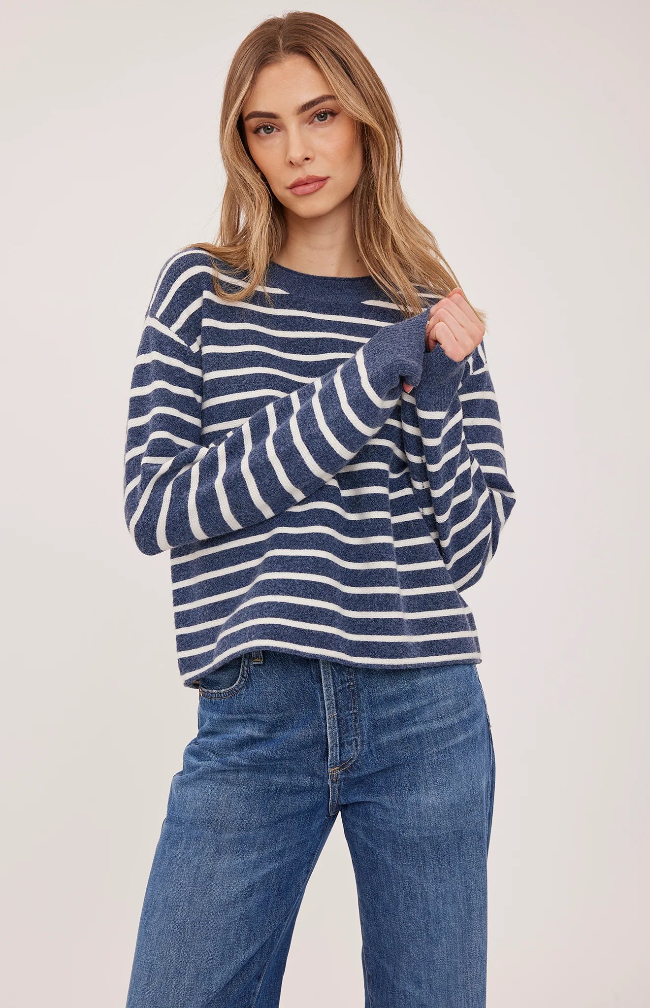 Relaxed navy and white striped long-sleeve sweater with rolled neckline, paired with wide-leg jeans