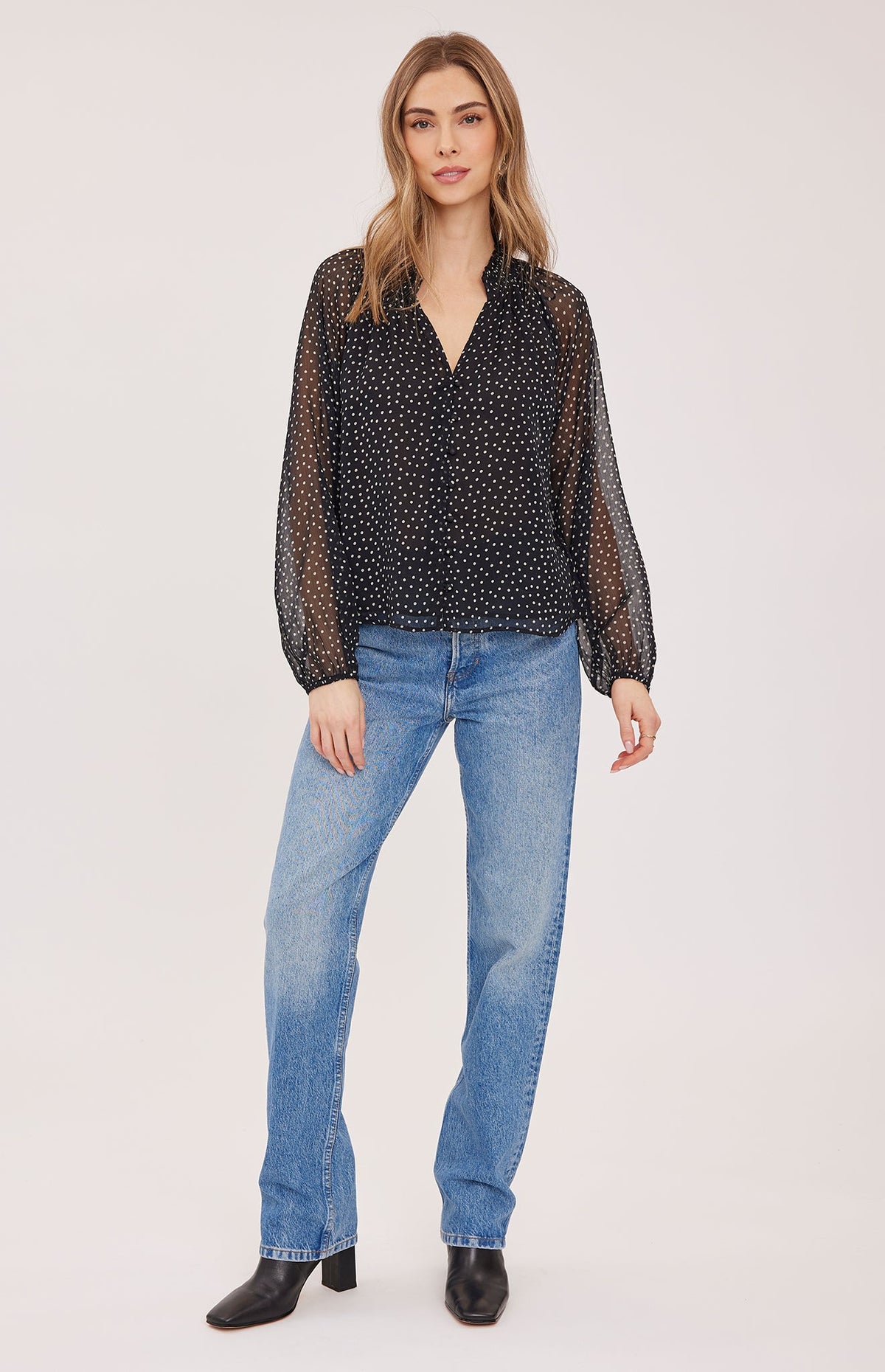 Model wearing Gentle Fawn Annie black polka dot sheer long-sleeve blouse with blue jeans