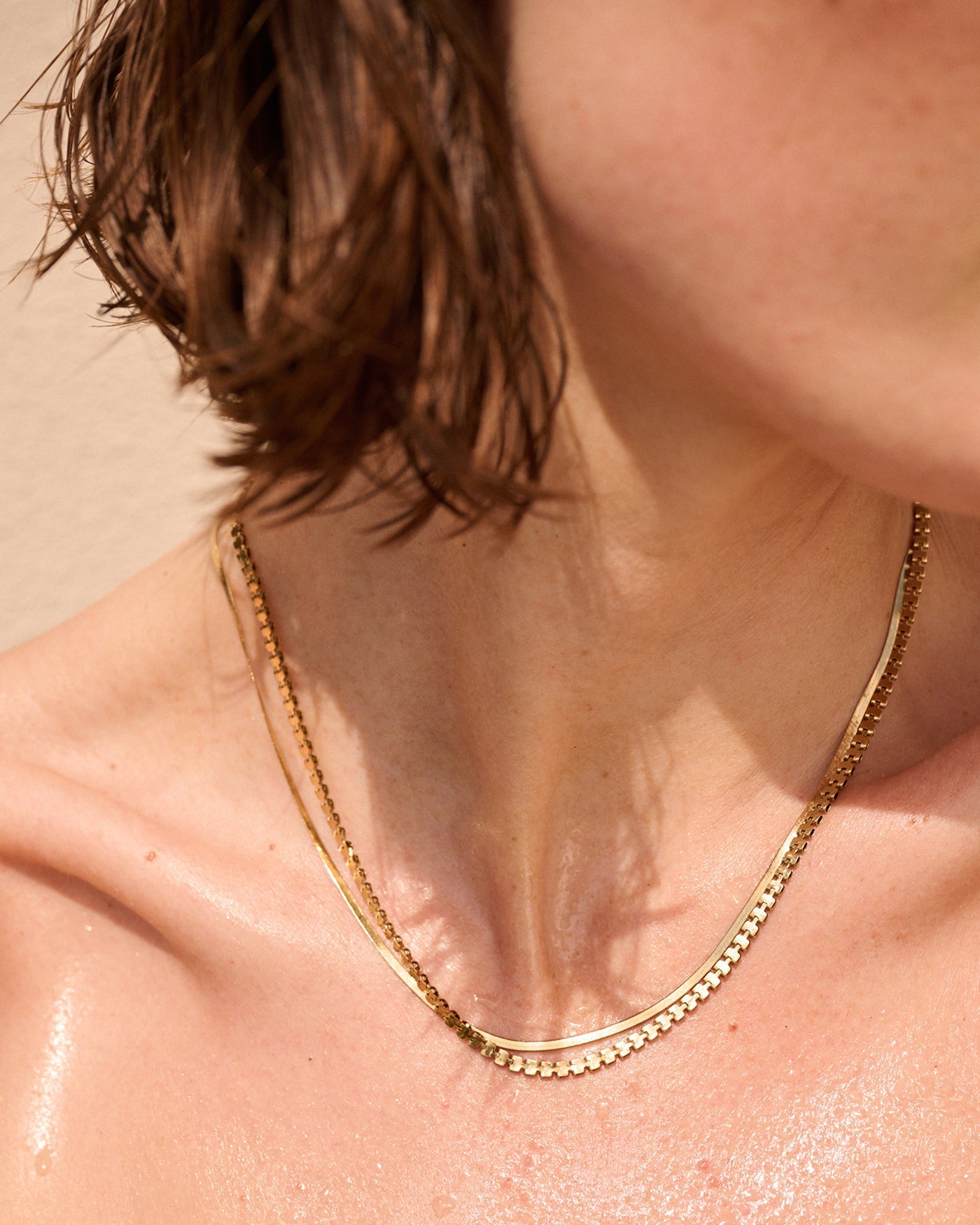 Model wearing Jenny Bird Double Amalfi layered gold chain necklace on bare dewy skin