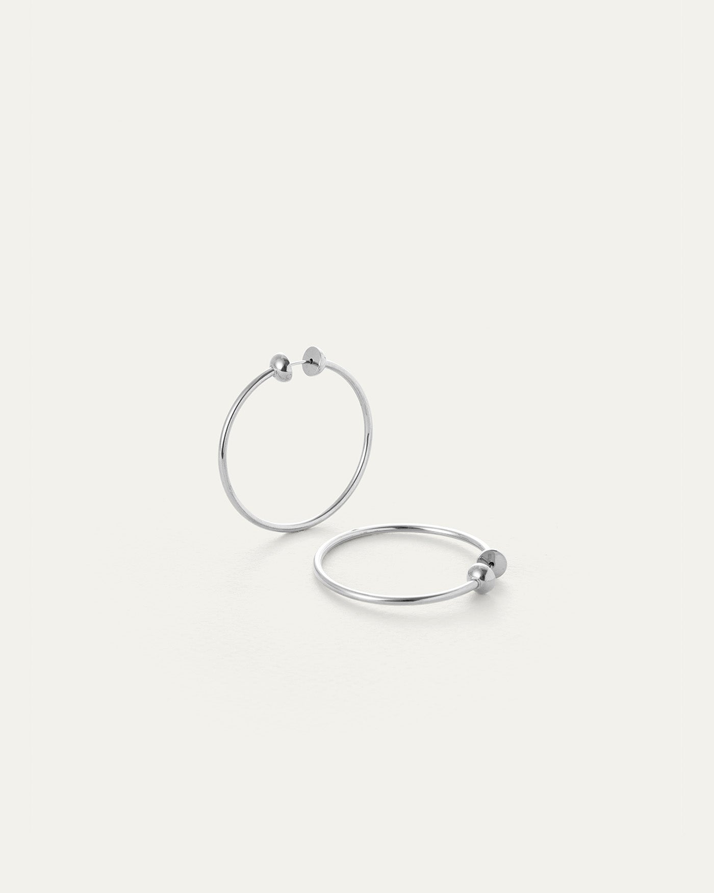 Pair of silver mini hoop earrings with small ball detail on white background