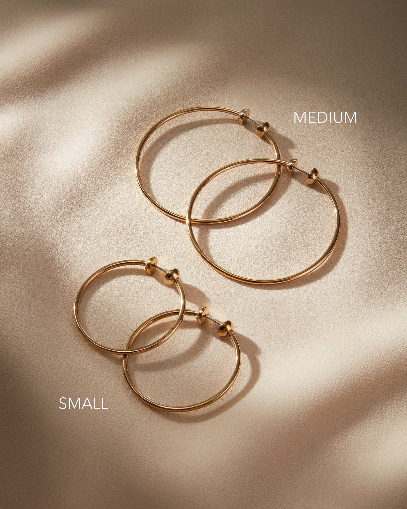 Jenny Bird Mini Icon Hoops in gold shown in small and medium sizes on neutral background