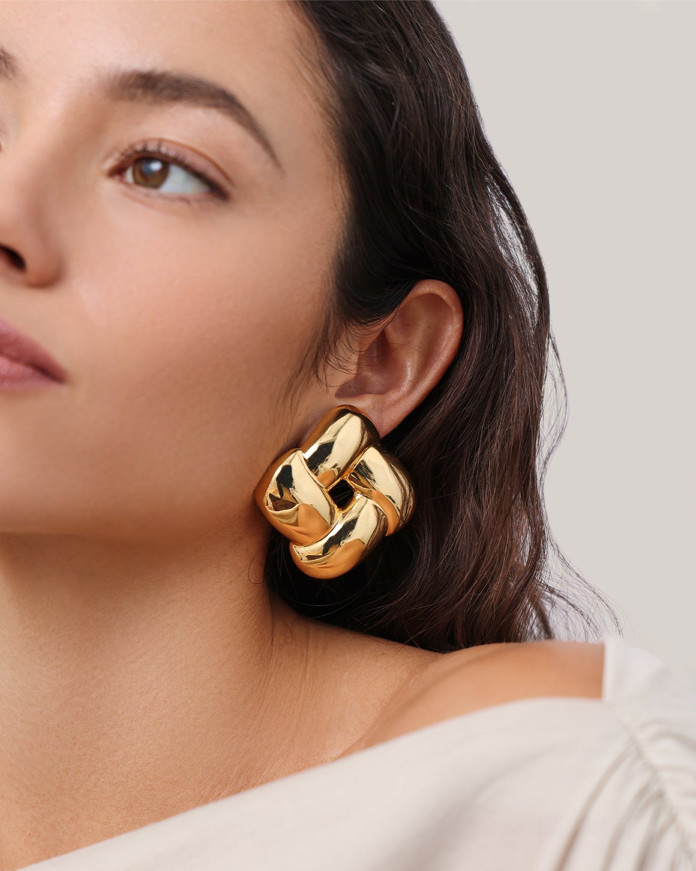 Model wearing large gold sculptural knot stud earring by Jenny Bird on ear