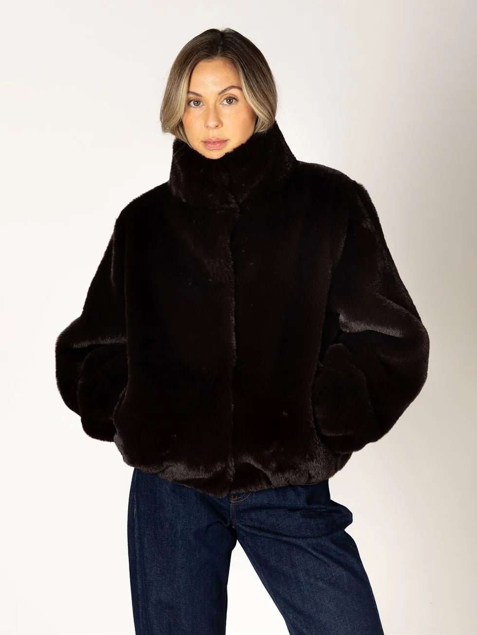 Kendra dark brown faux fur bomber jacket with stand collar, worn with jeans