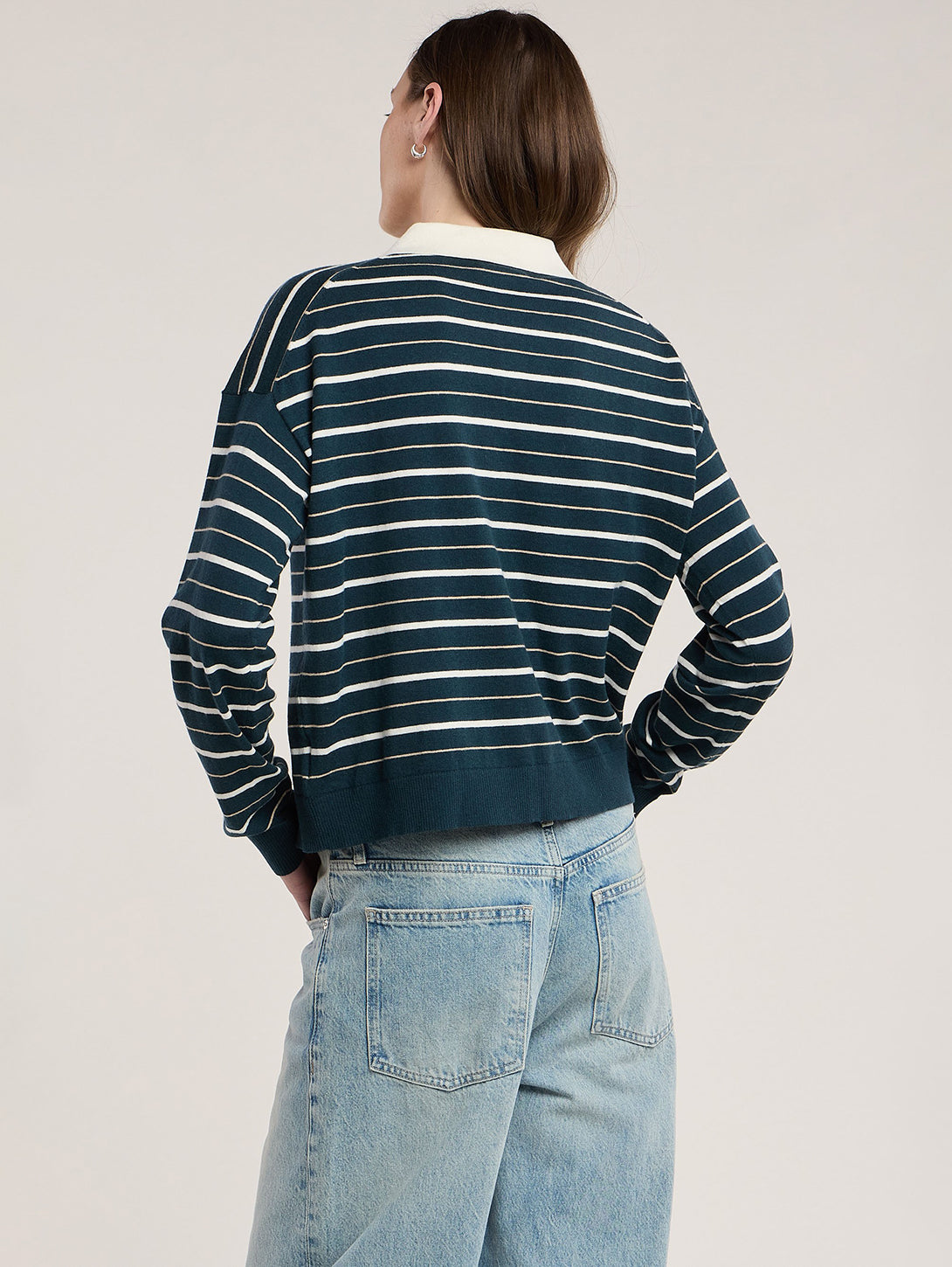 Back view of model wearing teal and cream striped cropped sweatshirt with wide-leg jeans