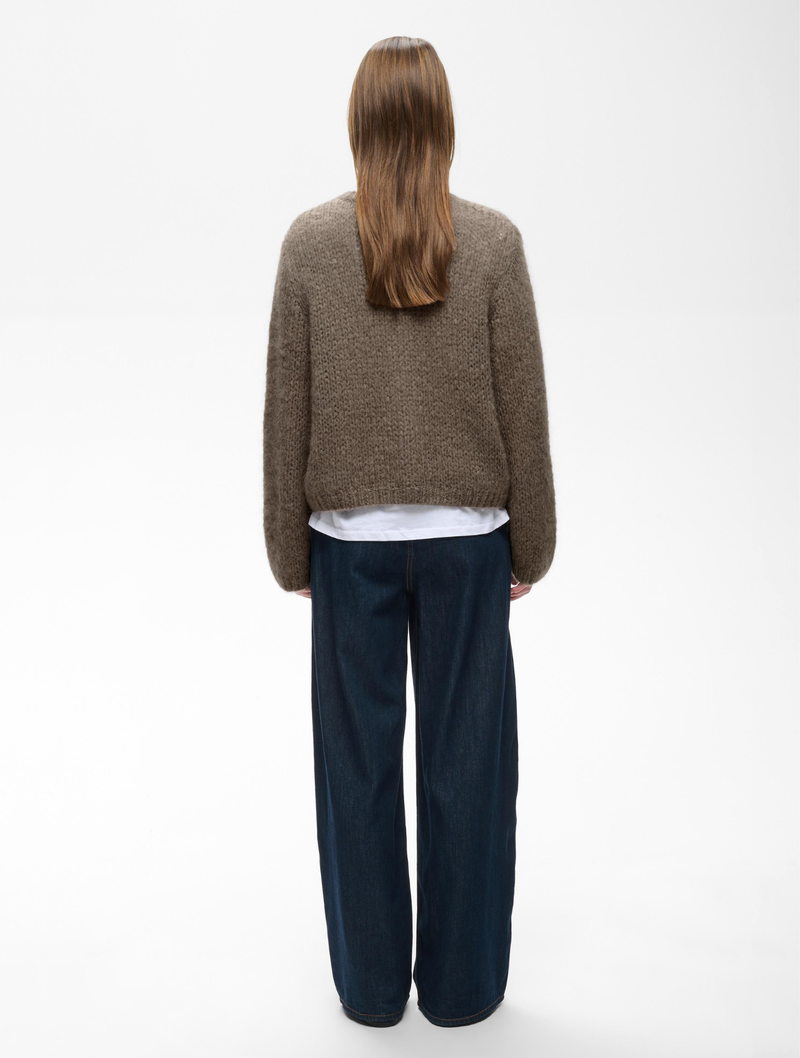Jetra brown chunky knit cardigan worn over white shirt with wide-leg jeans, back view.