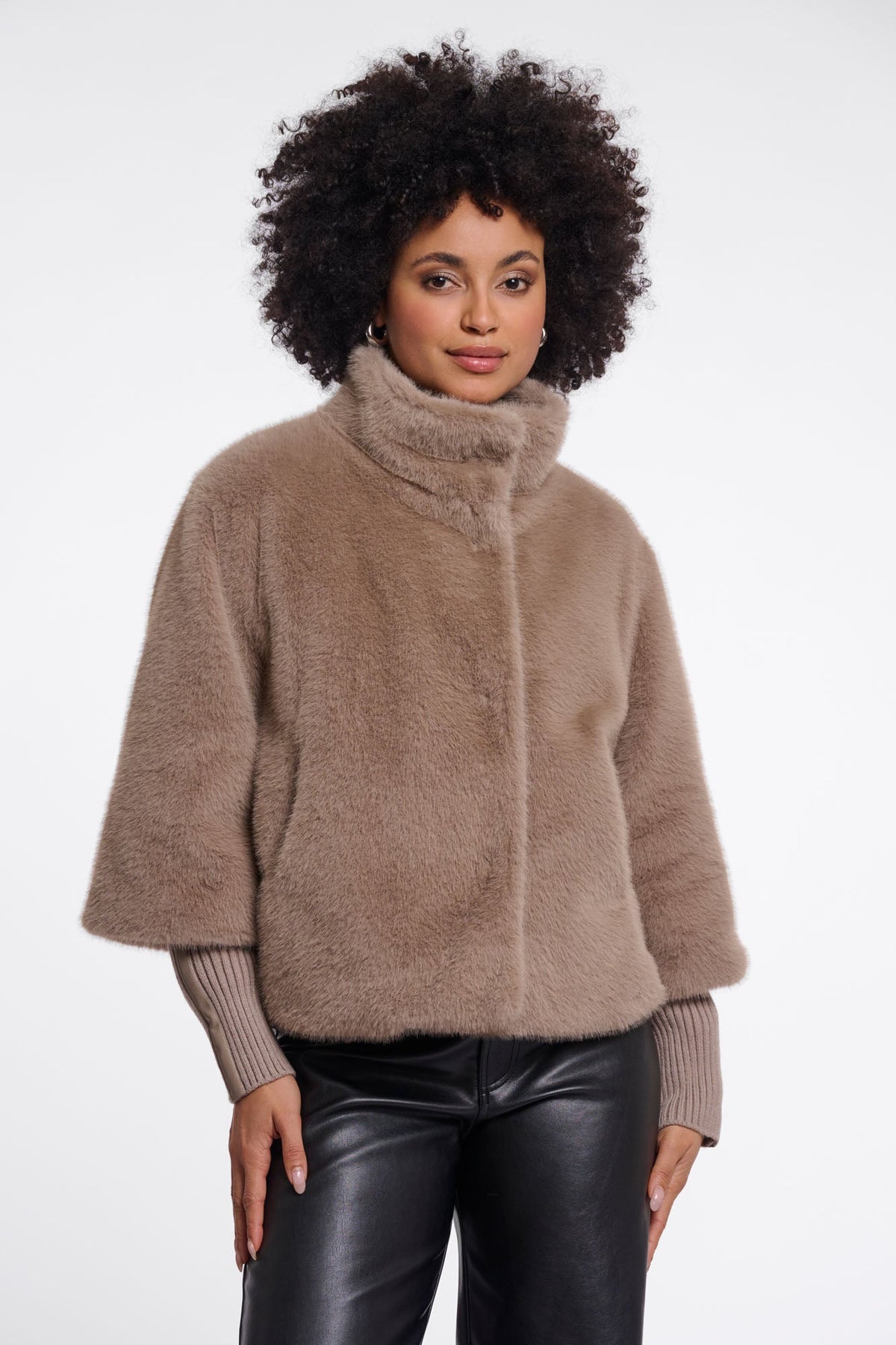 Woman wearing RINO & PELLE Nesrin faux fur jacket in mocha latte with ribbed cuffs and black leather trousers.