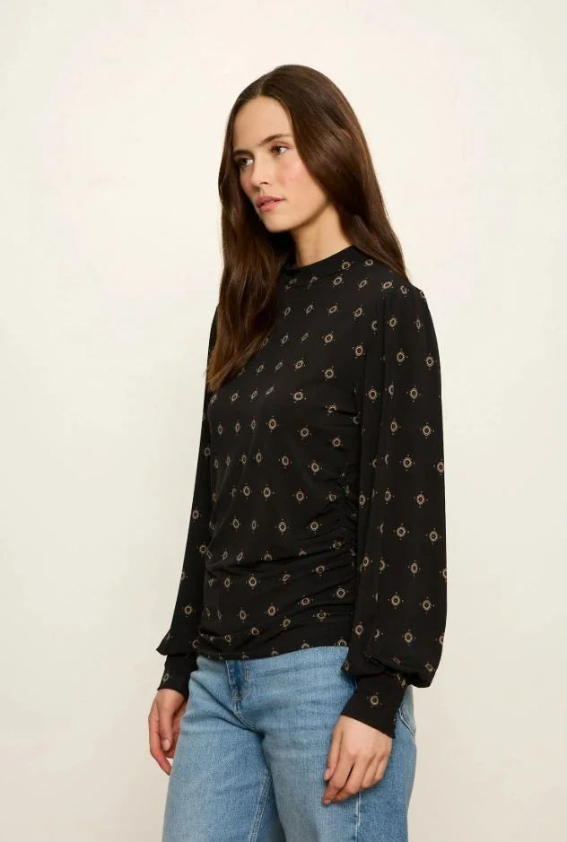 Black long-sleeve mock neck top with gold geometric print and cinched side detail