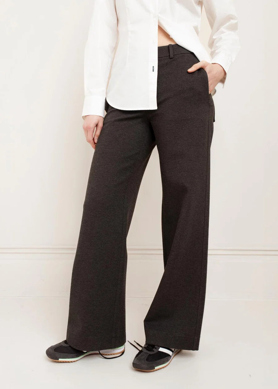 Dark brown wide-leg trousers with side pockets styled with a white button-up shirt and sneakers