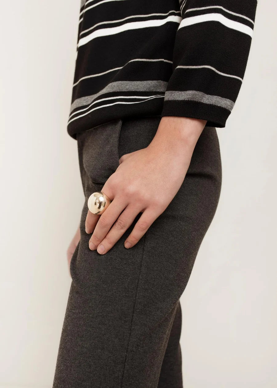 Black striped knit crew neck sweater with white and grey stripes, worn with grey trousers