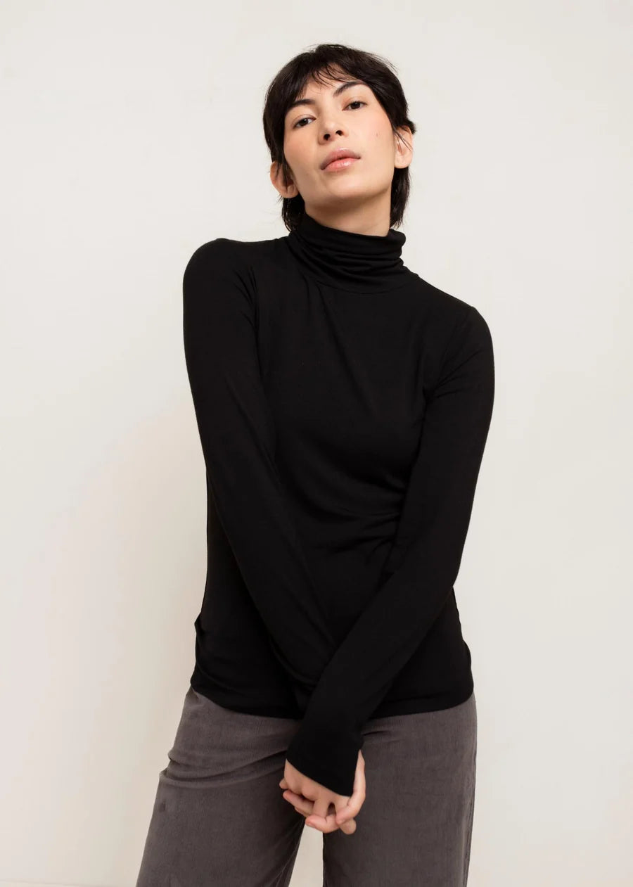 Black fitted long-sleeve turtleneck top worn with grey pants