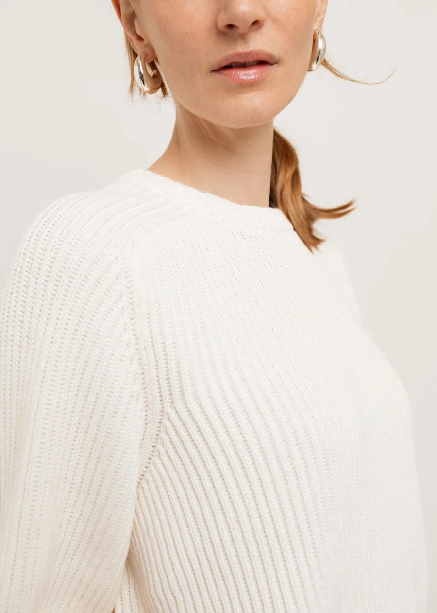 White ribbed knit crew neck sweater with long sleeves, close-up detail view