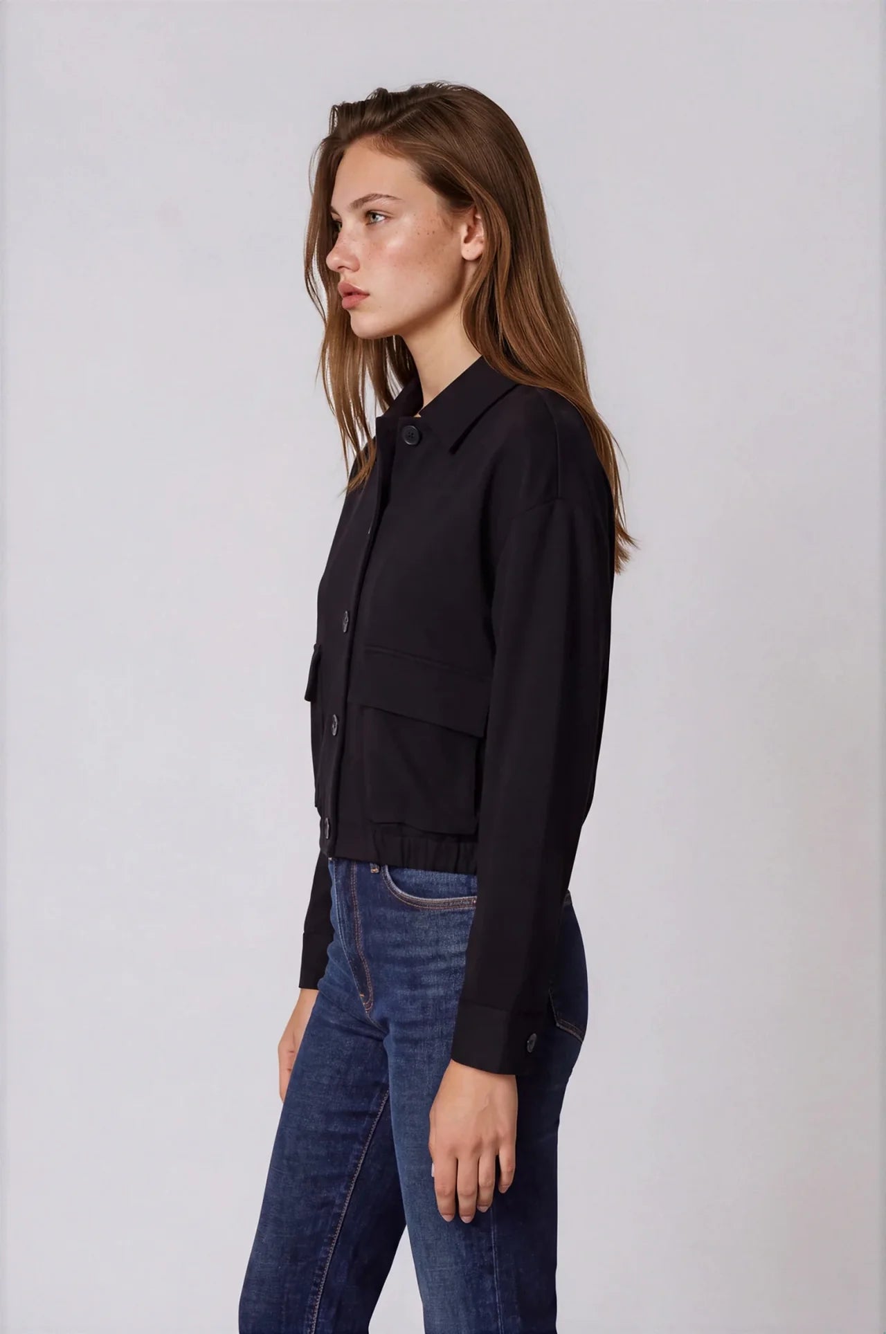 Black scuba bomber jacket with collar, front buttons, and patch pockets, styled with jeans.