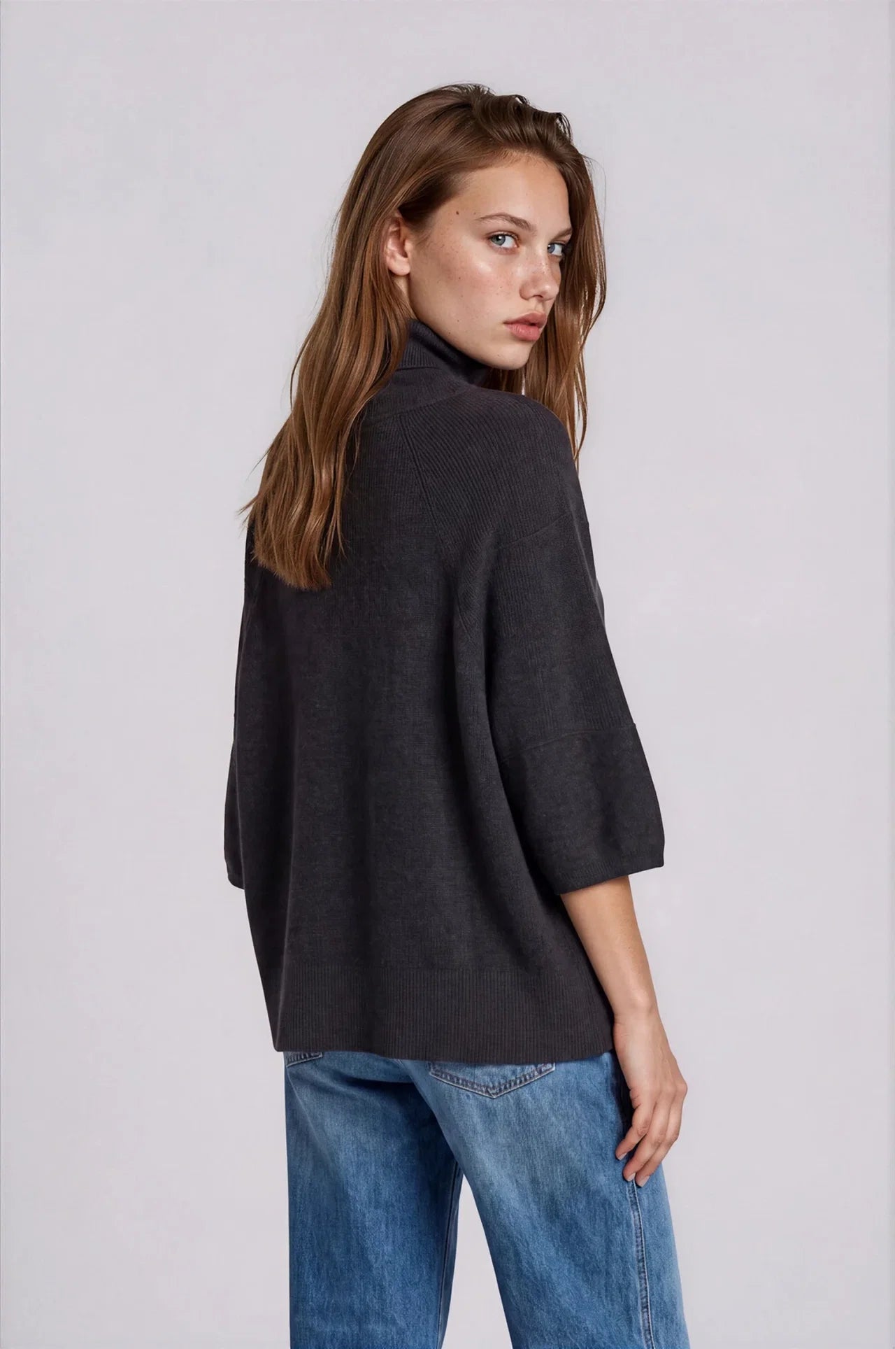 Charcoal oversized turtleneck sweater with 3/4 sleeves, back view, paired with blue jeans