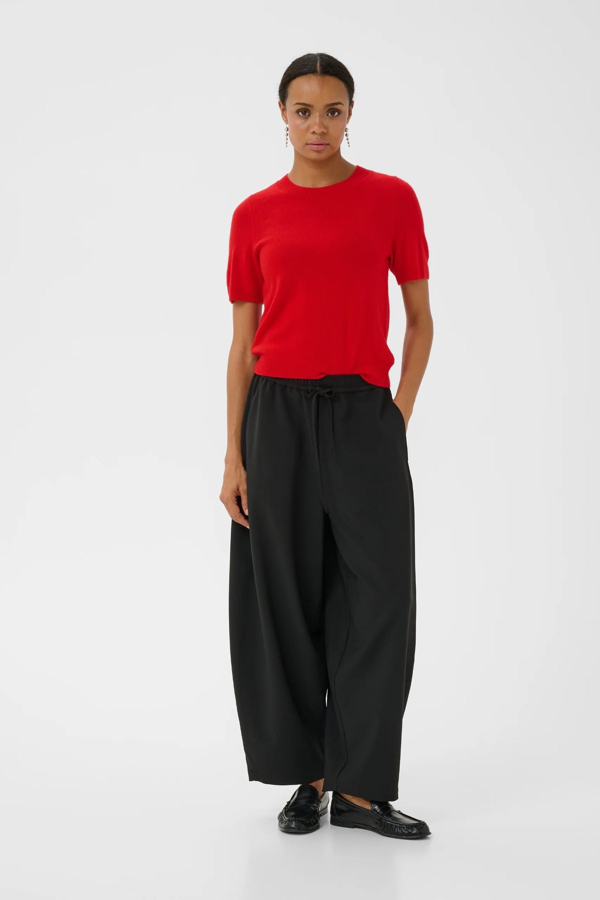 Red short-sleeve knit pullover with crew neck, styled with black wide-leg trousers