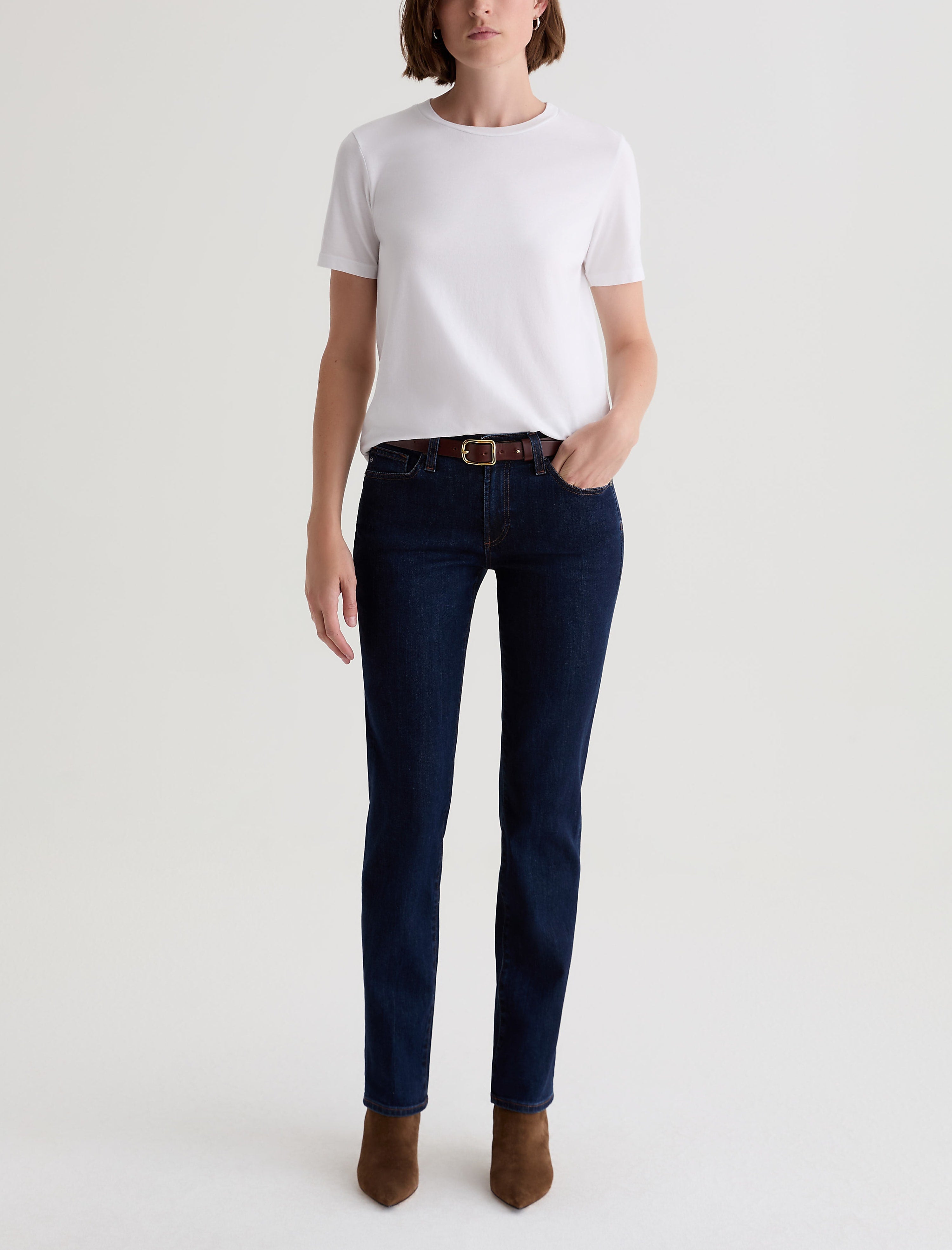 Woman wearing AG Sandra straight-leg jeans in deep modern indigo with white tee and brown belt