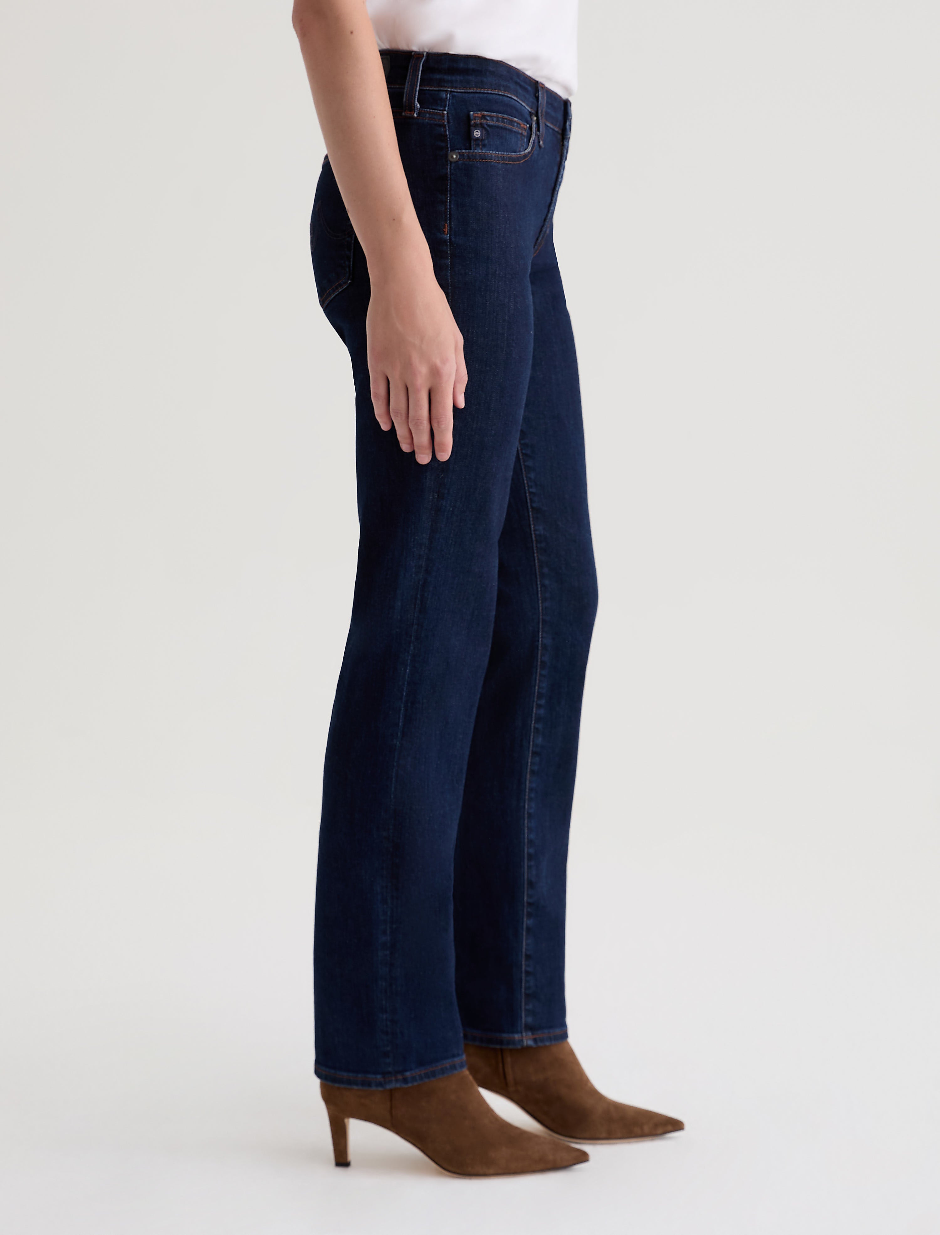Side view of AG Sandra straight-leg jeans in deep modern indigo wash with brown suede heeled boots