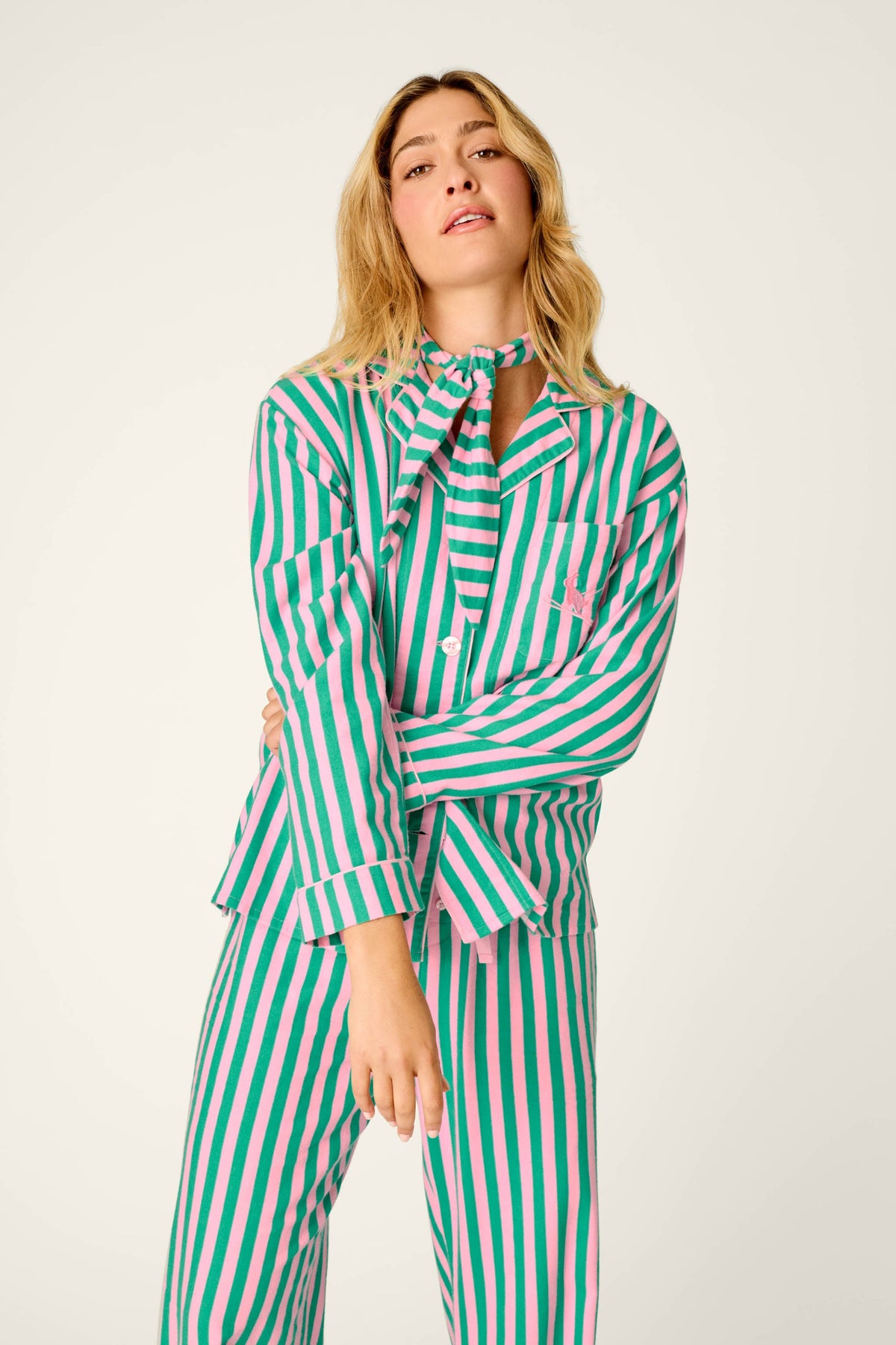 Model wearing pink and green striped long-sleeve pajama set with matching pants and neck tie