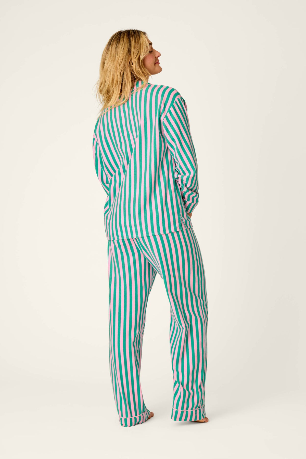 Model wearing PJ Salvage striped pajama set in pink and green, back view
