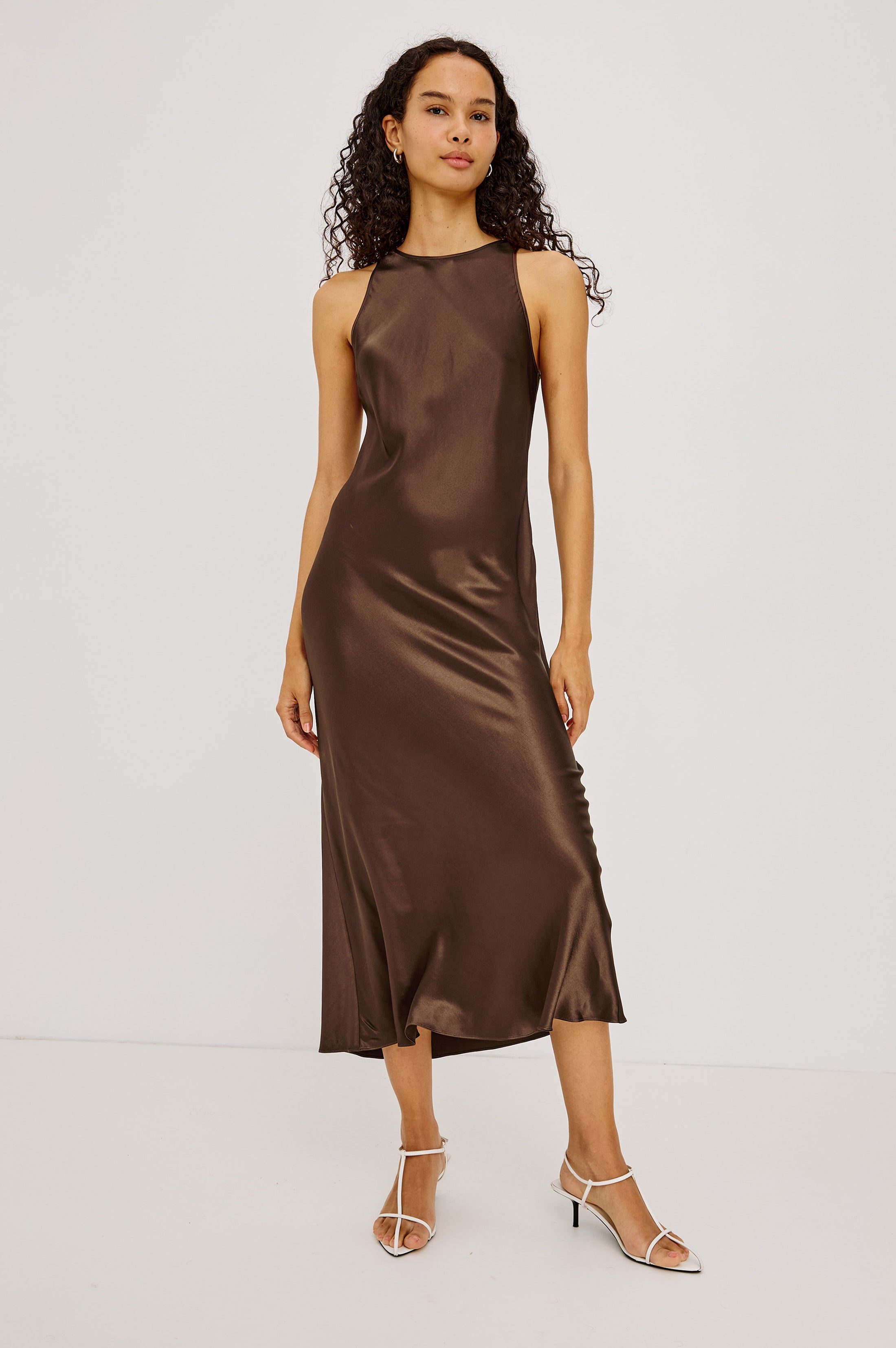 Model wearing Rails Solene Espresso satin midi slip dress with white strappy heels
