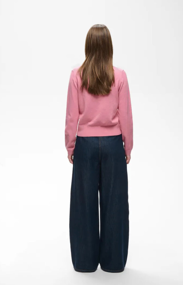 Pink long-sleeve knit pullover sweater, rear view, worn with wide-leg dark jeans