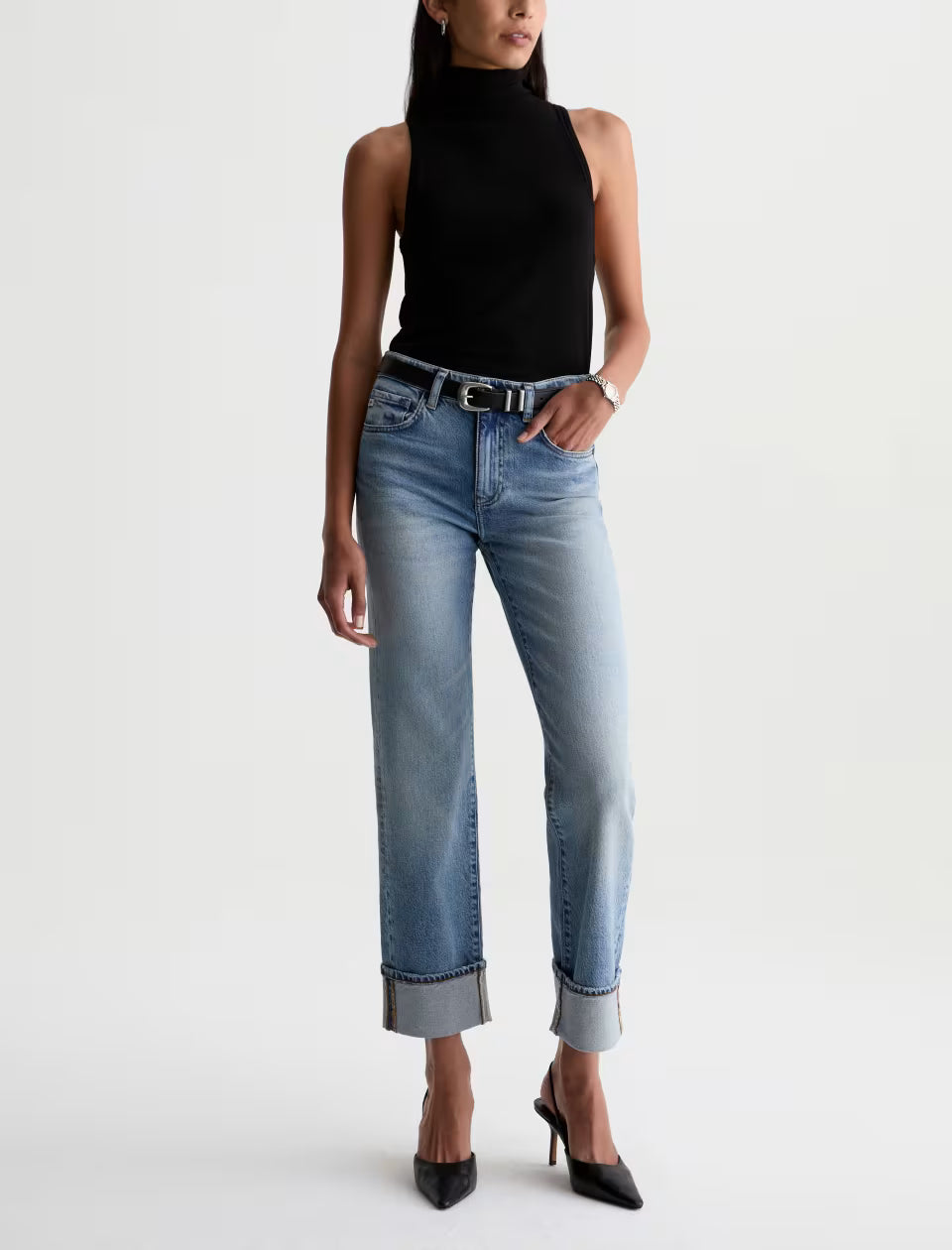 Light blue mid-rise straight leg cuffed jeans with black sleeveless turtleneck top and heels