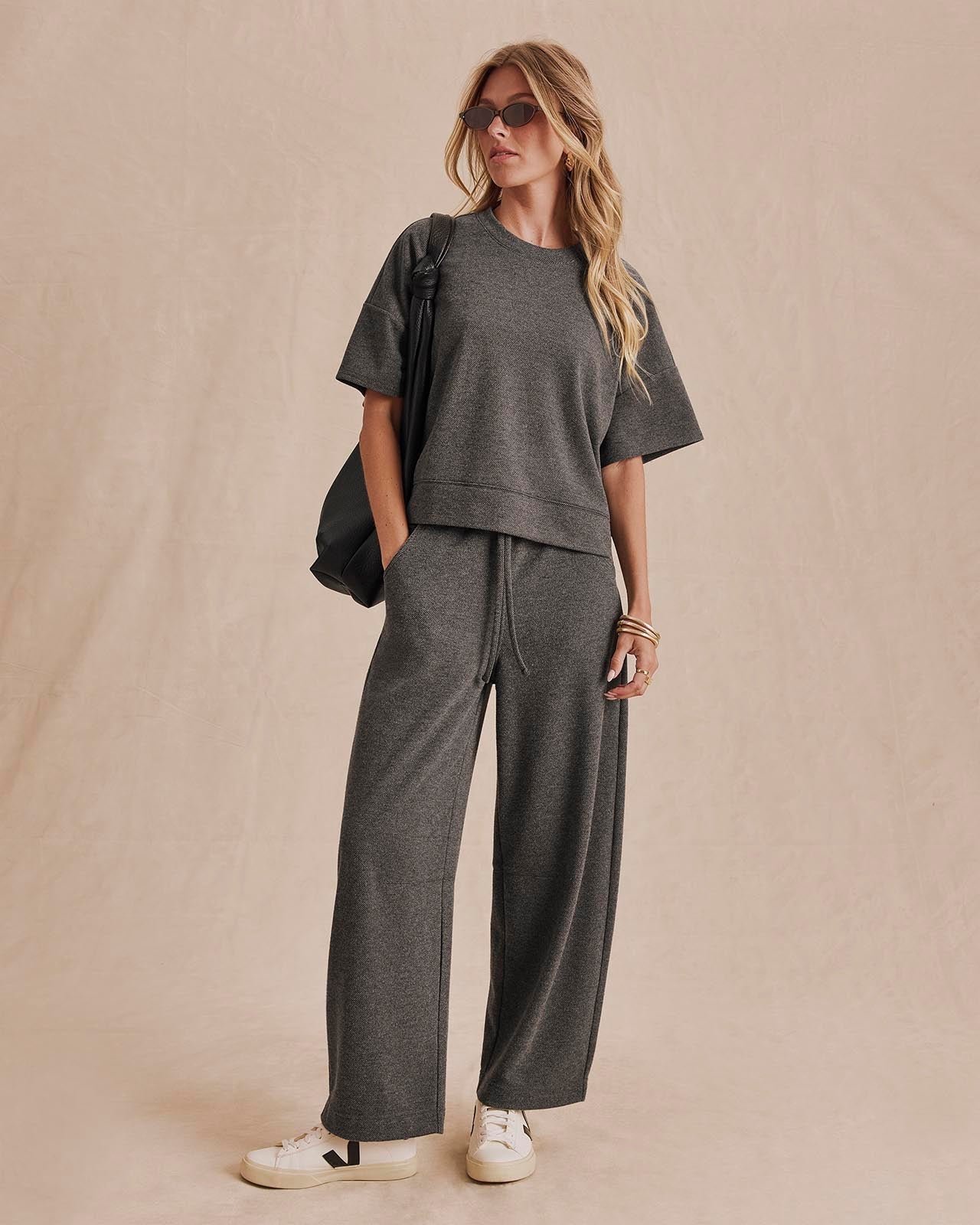 Woman wearing charcoal knit short-sleeve top with matching wide-leg pants and white sneakers