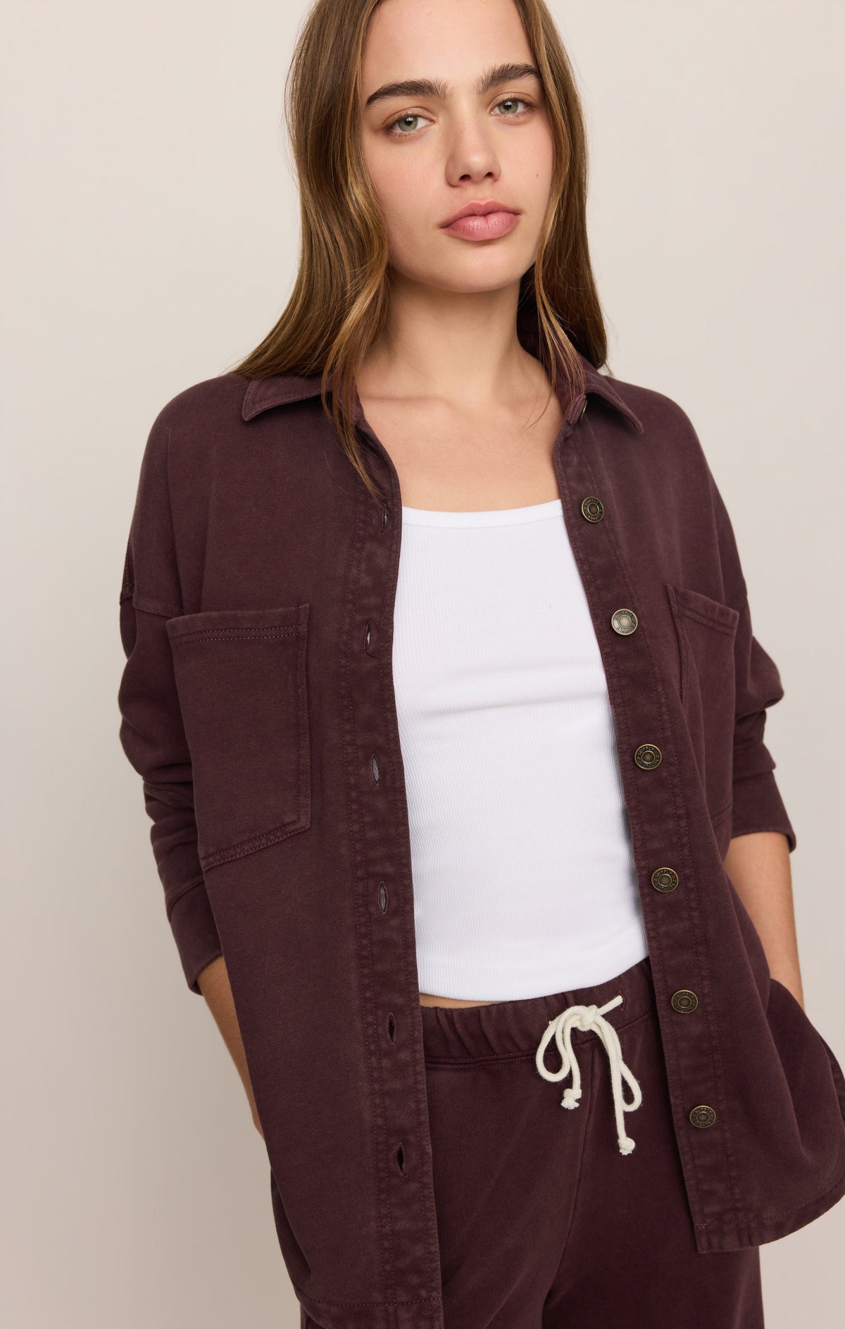 Model wearing Z Supply All Day Knit Jacket in Berry Noir, open over white crop top