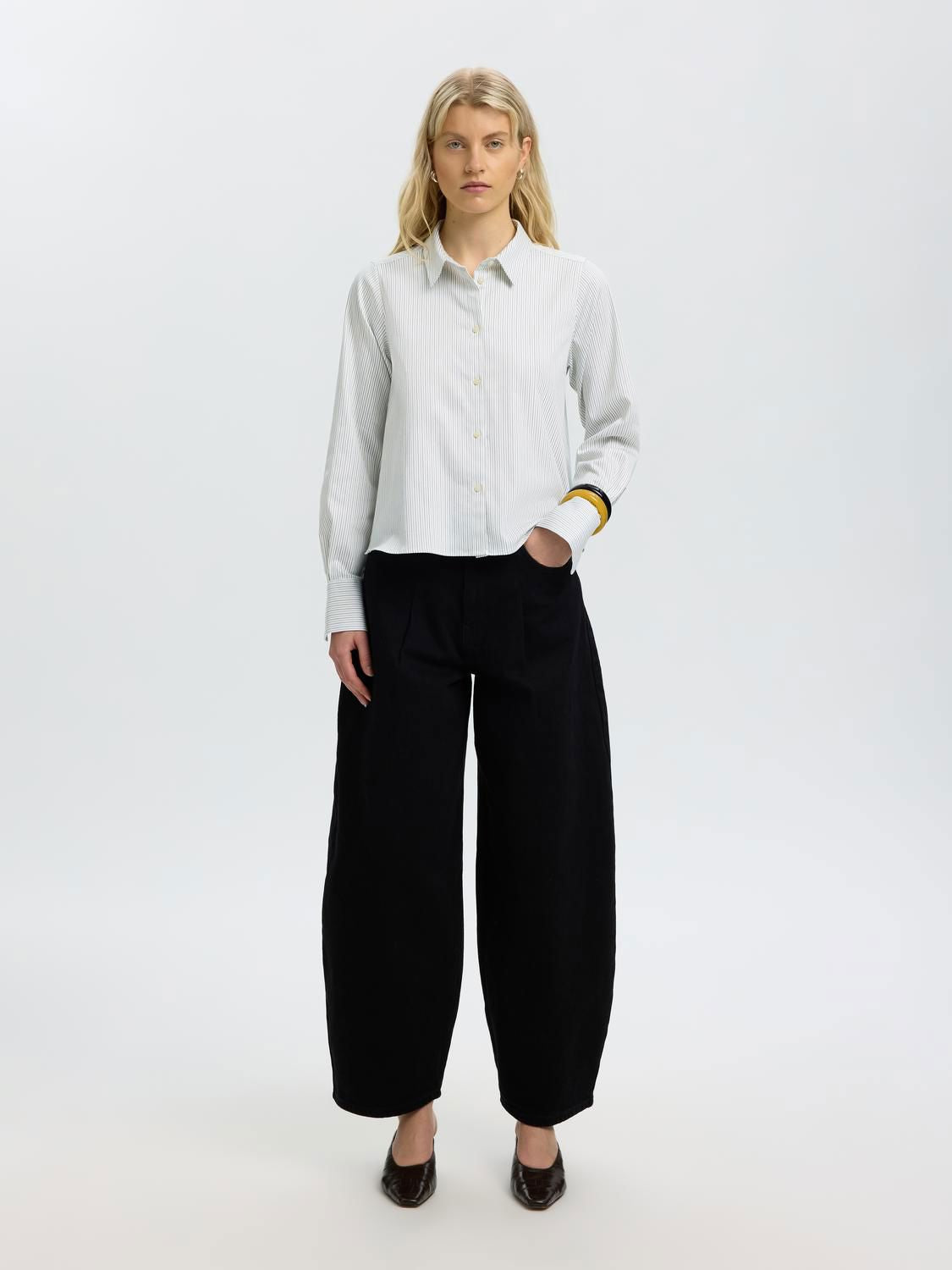 Model wearing SELECTED SLWROMIE relaxed striped shirt in white and light blue stripes with yellow cuff detail