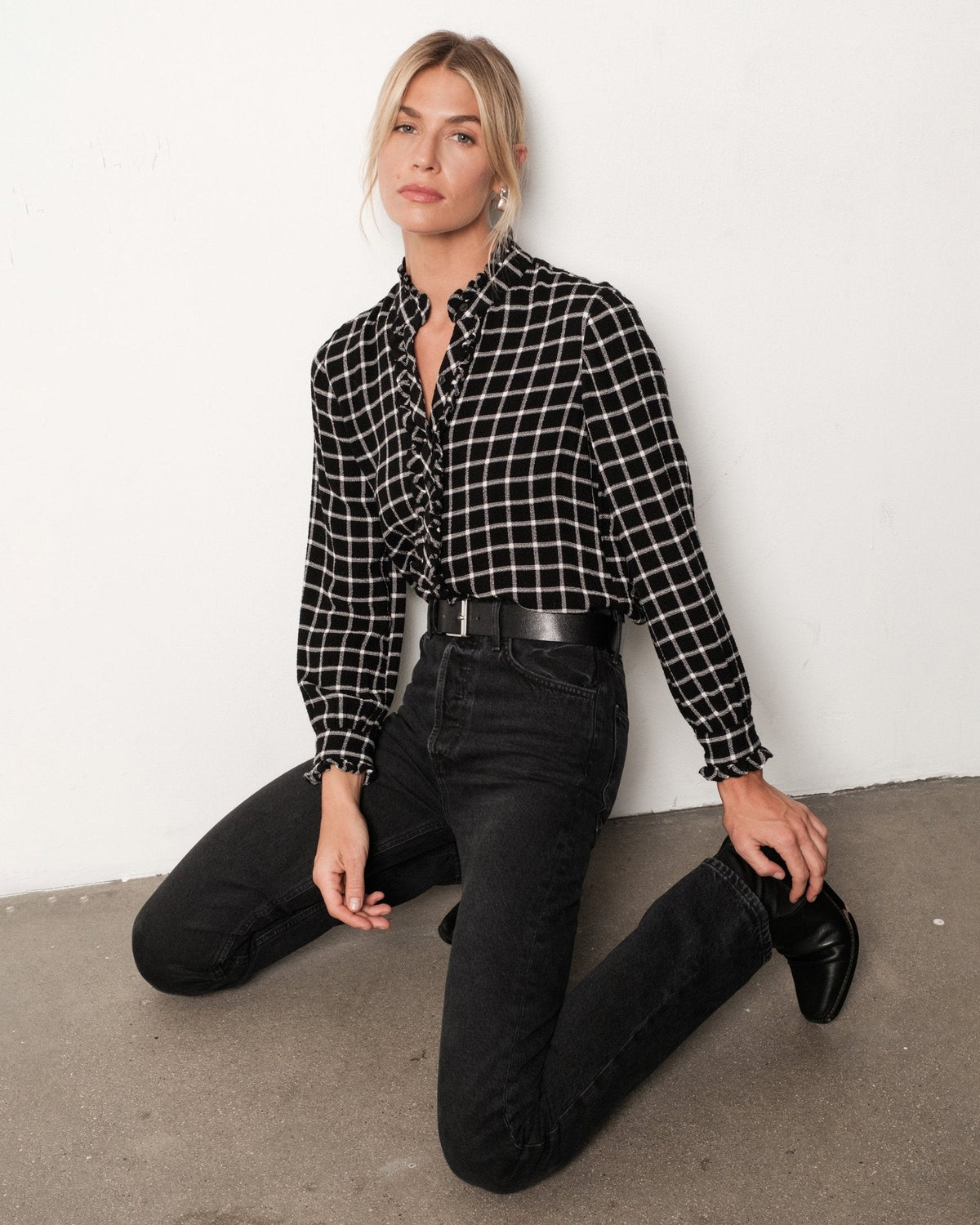 Model wearing Bella Dahl black and white plaid button-down shirt with ruffle edges and black jeans