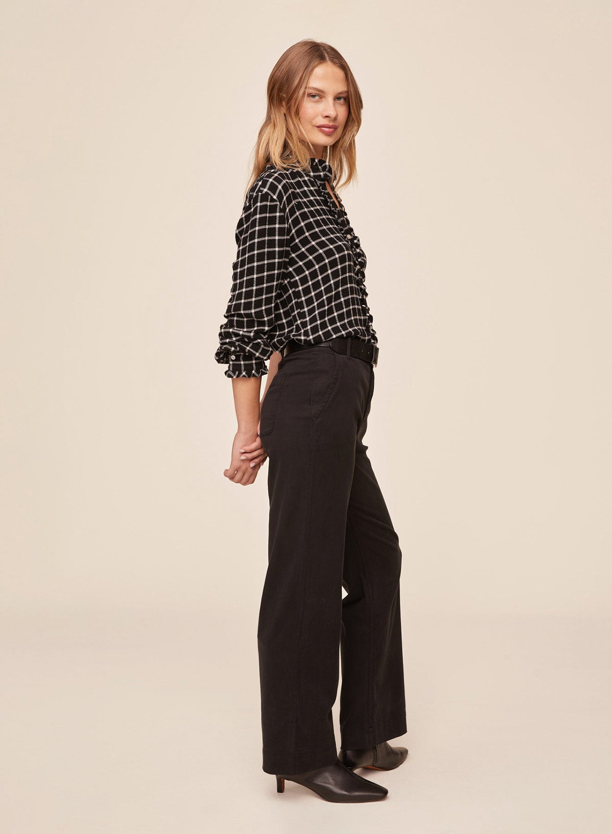 Model wearing Bella Dahl black and white plaid button down shirt with ruffle edges, side view