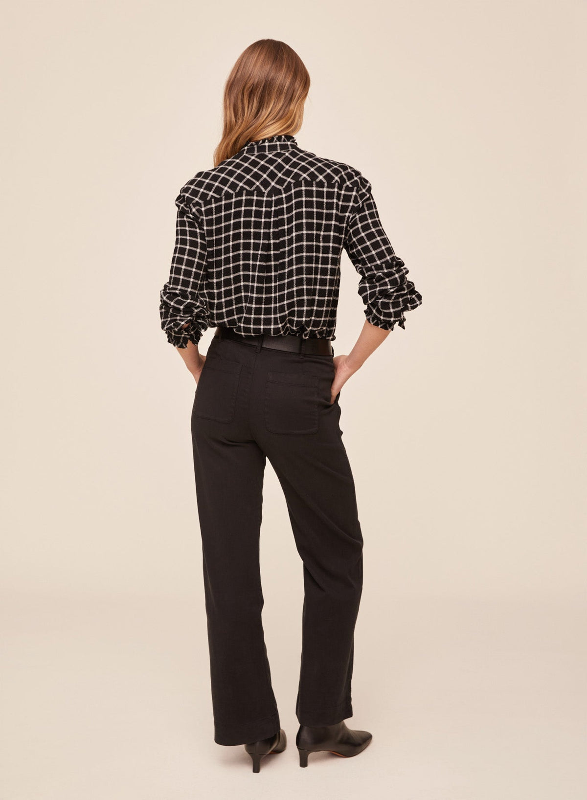 Back view of model wearing Bella Dahl black and white plaid button down shirt with ruffle edges