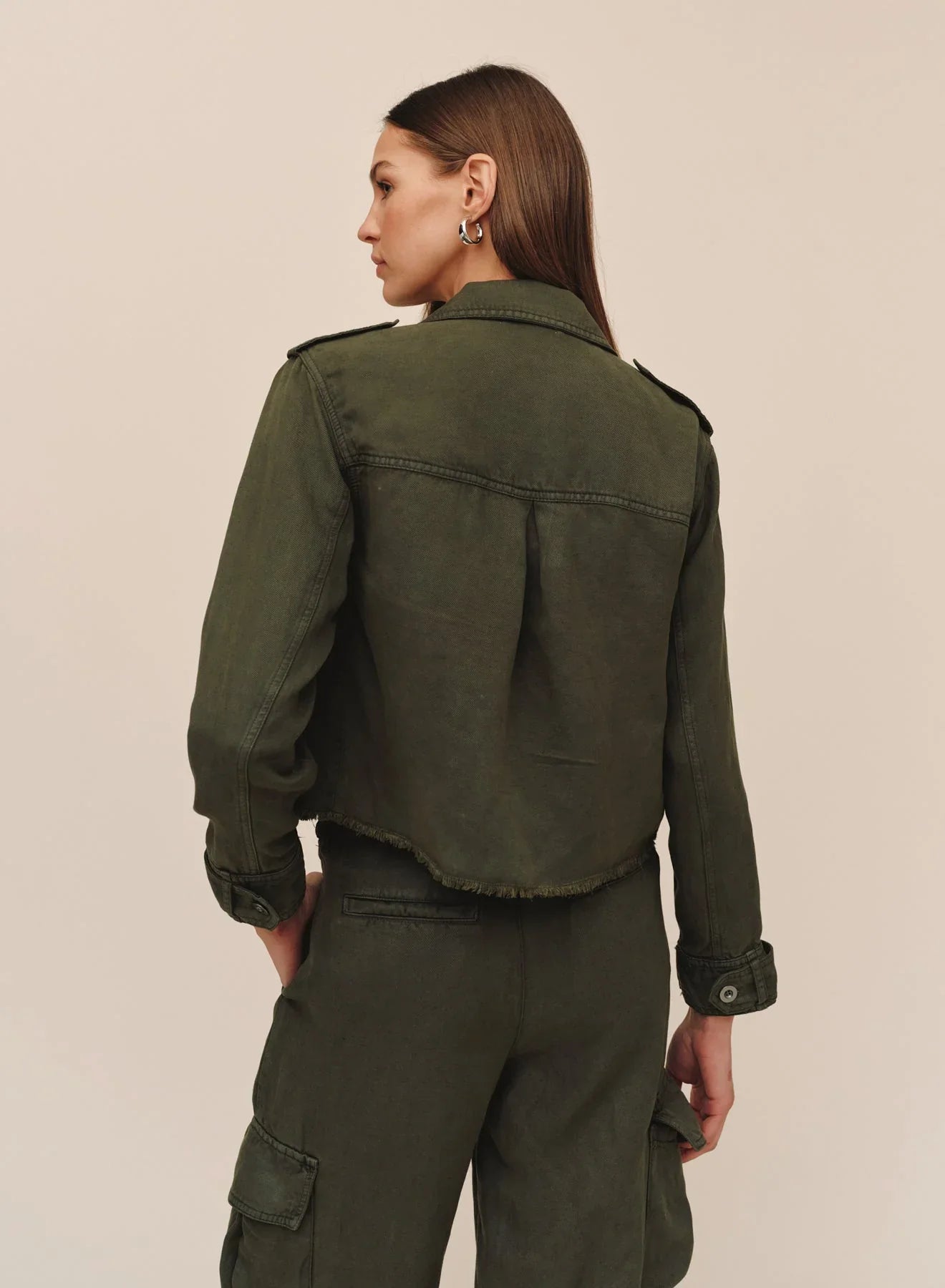 Back view of cropped olive utility jacket with fray hem and epaulettes on model