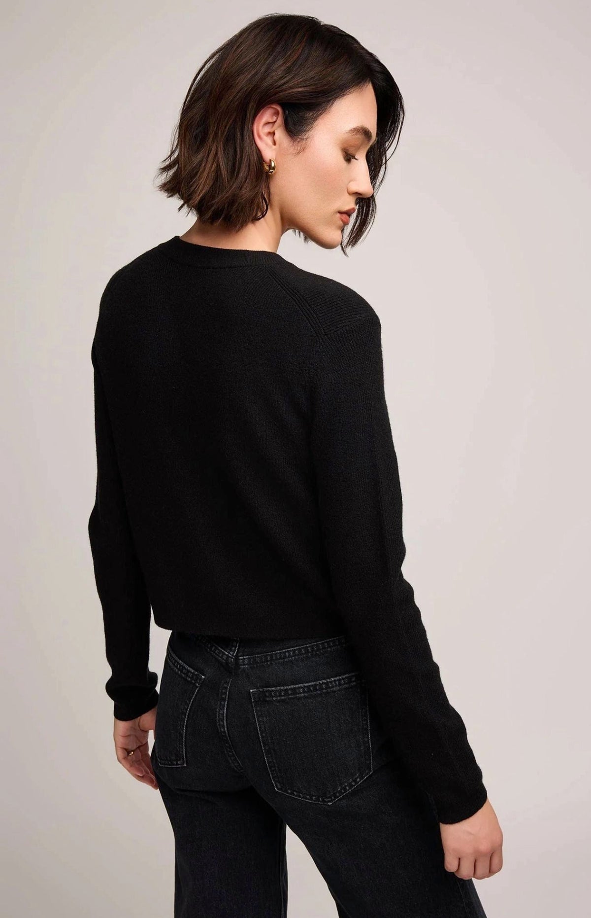 Back view of woman wearing Gentle Fawn Mirabelle black knit sweater with dark jeans