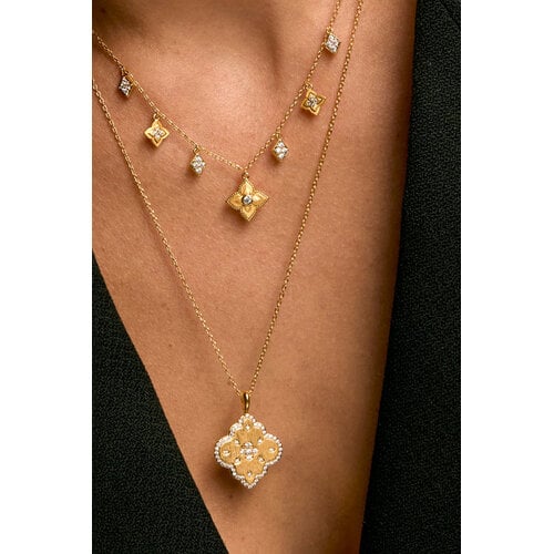 Model wearing layered gold Lotus Liberty necklaces with floral and diamond-shaped pendants