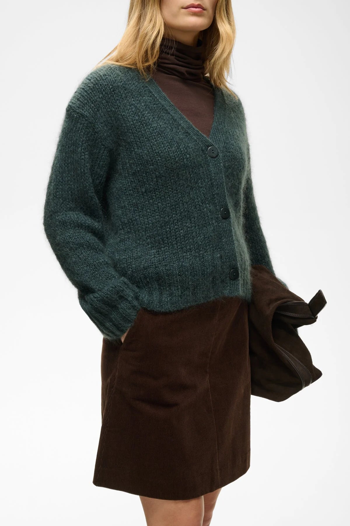 Dark brown corduroy mini skirt with side pockets, worn with green cardigan